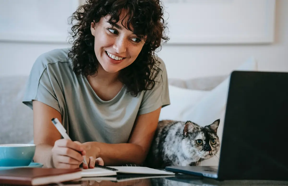 Une femme avec son chat, qui travaille devant un ordinateur